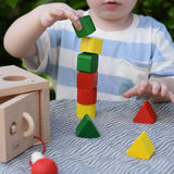Child stacking the green yellow and red blocks from the Nic lock a bloc wooden shape sorter toy on top of each other.