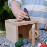 Child posting a Grapat tomten Nin through the circular slot in the top of the Nic lock a bloc wooden shape sorter toy.