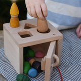 Child posting Grapat Nins and mandala pieces through the slots on the Nic lock a bloc wooden shape sorter toy.