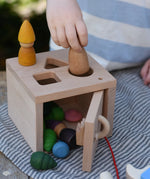 Child posting Grapat Nins and mandala pieces through the slots on the Nic lock a bloc wooden shape sorter toy.