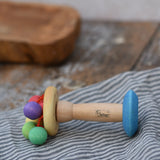 Nic organic carousel rattle spinning baby grasping toy placed sideways on a striped cloth.