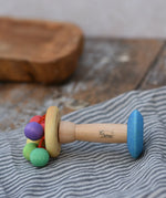 Nic organic carousel rattle spinning baby grasping toy placed sideways on a striped cloth.