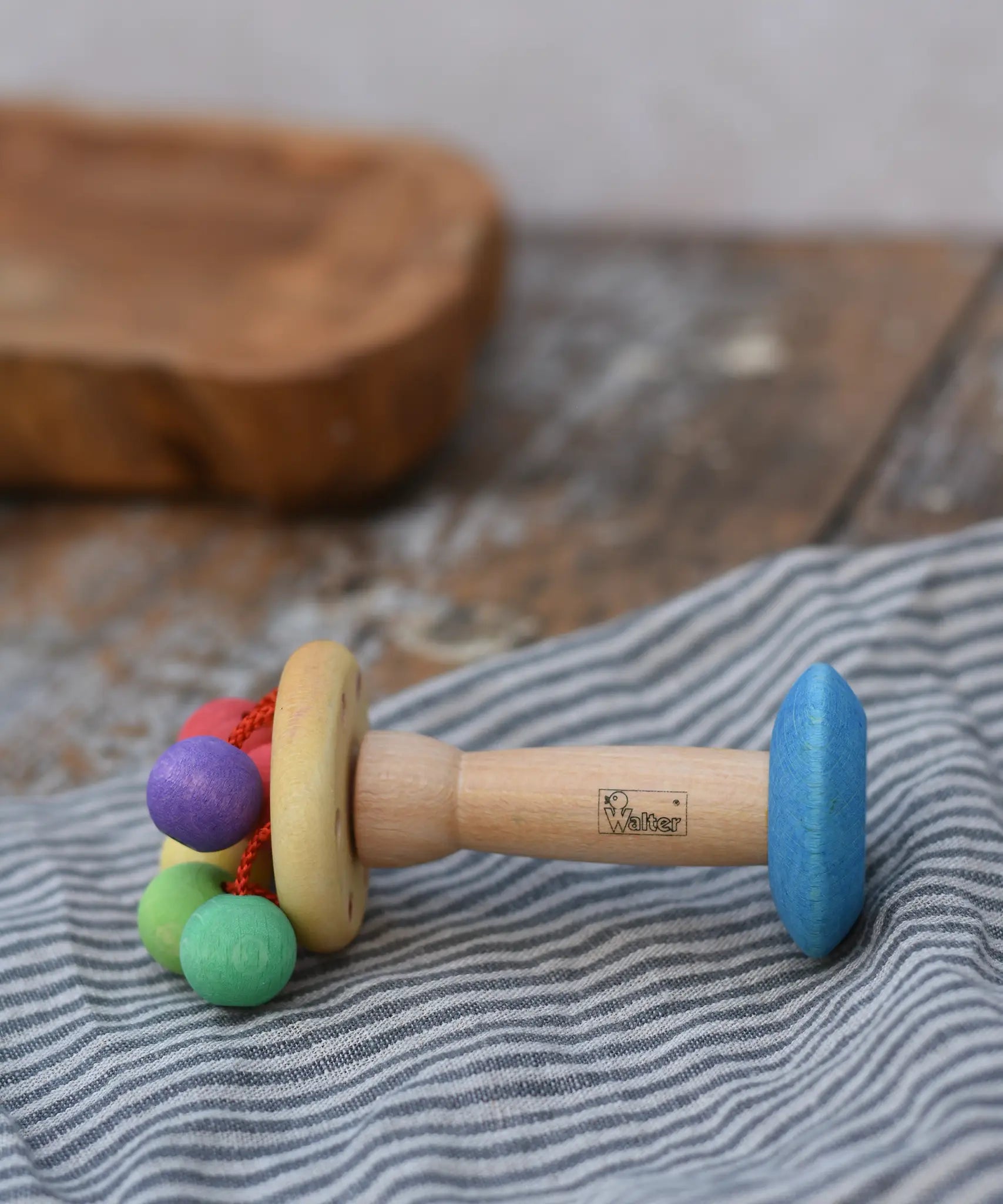 Nic organic carousel rattle spinning baby grasping toy placed sideways on a striped cloth.