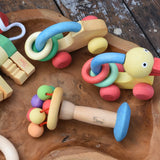 Nic organic carousel rattle spinning baby grasping toy placed on a wooden dish with other baby toys from the Nic organic collection by Gluckskafer.