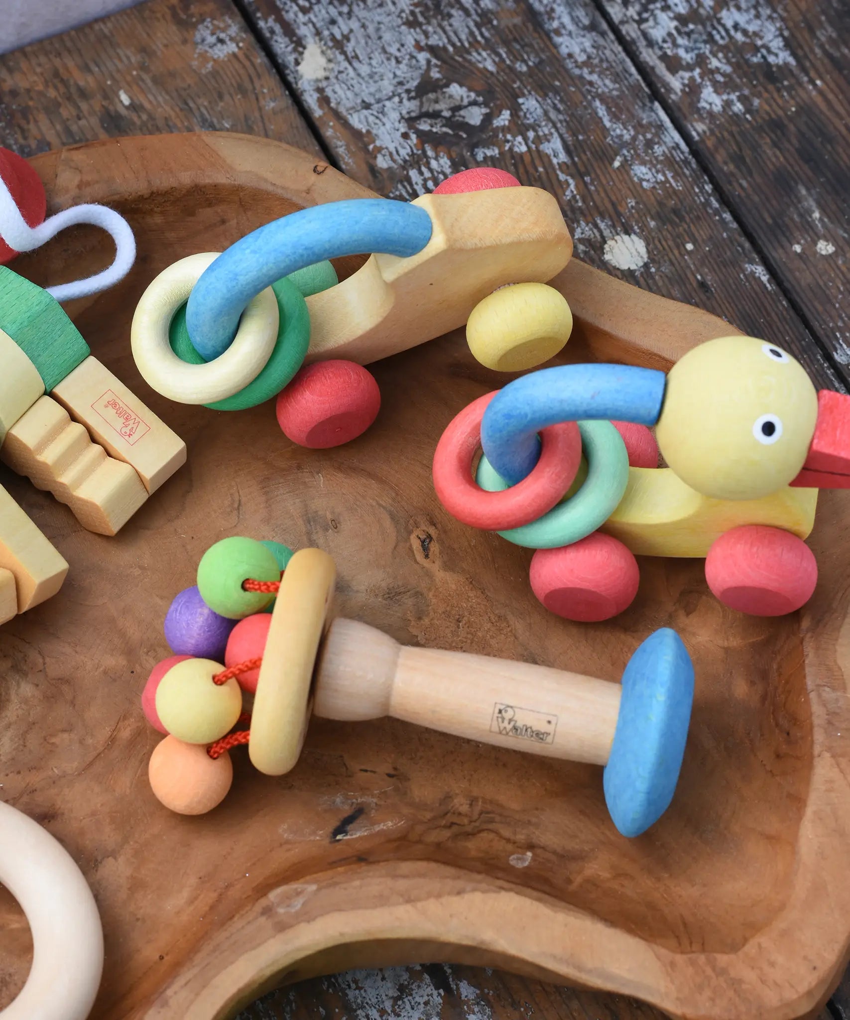 Nic organic carousel rattle spinning baby grasping toy placed on a wooden dish with other baby toys from the Nic organic collection by Gluckskafer.