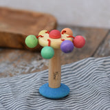 Nic organic carousel rattle spinning baby grasping toy placed upright on a striped cloth.