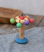 Nic organic carousel rattle spinning baby grasping toy placed upright on a striped cloth.