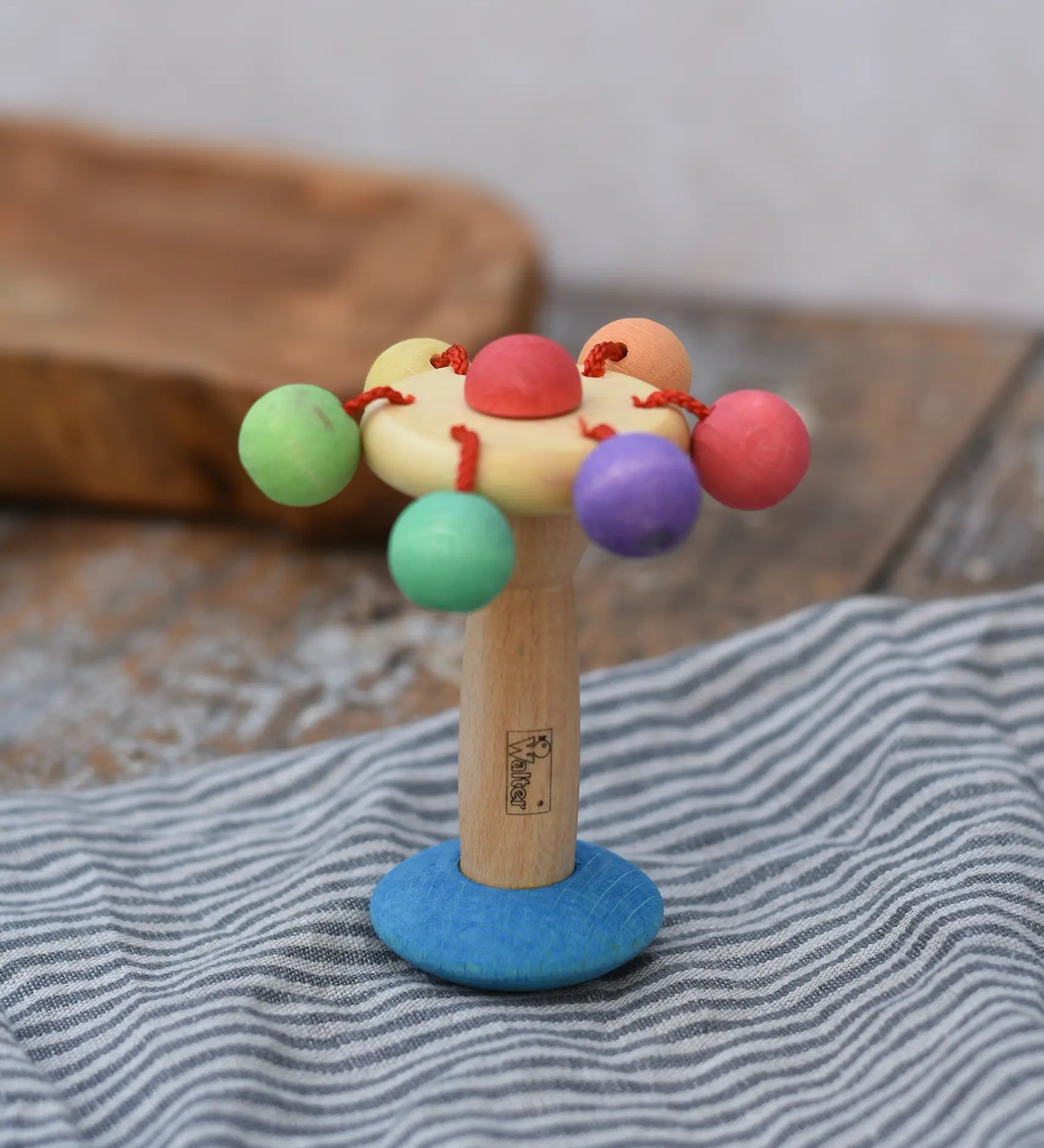 Nic organic carousel rattle spinning baby grasping toy placed upright on a striped cloth.