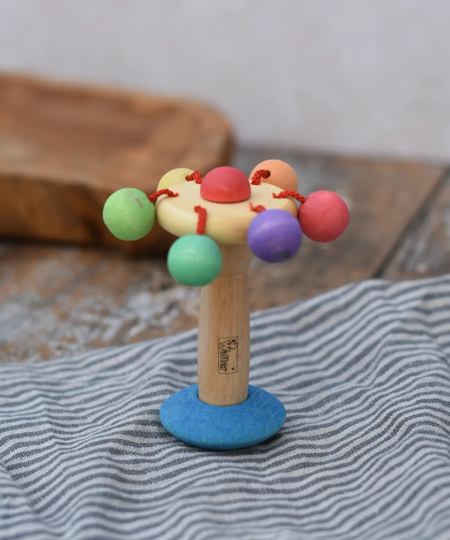 Nic organic carousel rattle spinning baby grasping toy placed upright on a striped cloth.