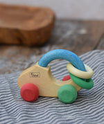 Nic organic grip car wooden baby toy placed on a striped grey cloth.