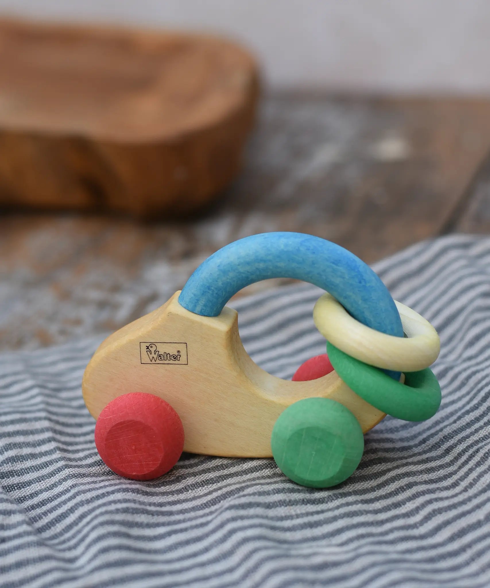 Nic organic grip car wooden baby toy placed on a striped grey cloth.