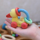 Nic organic grip duck wooden push along baby toy on a child's hand.