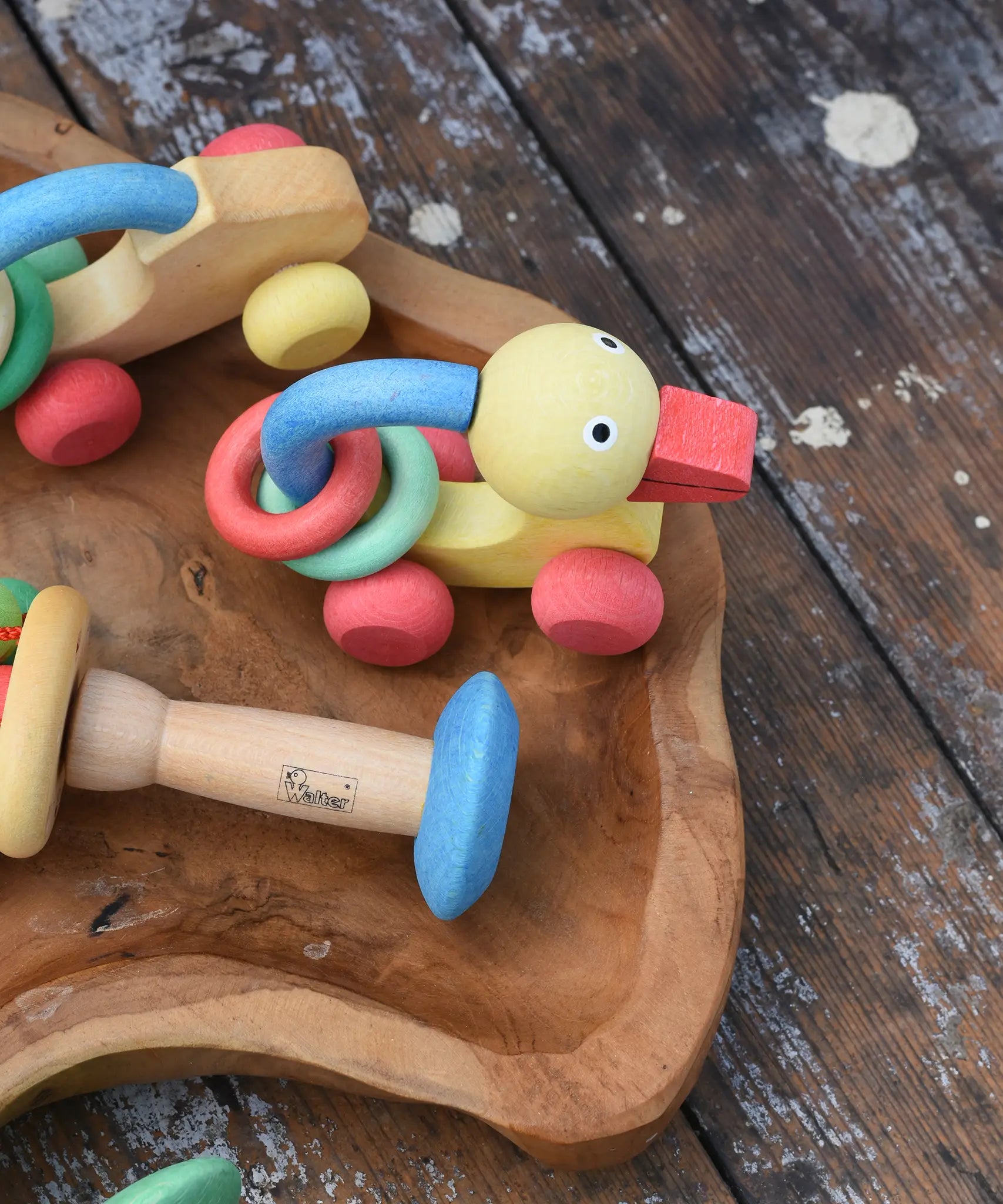 Nic organic grip duck wooden push along baby toy placed on a wooden dish next to other toys from the Gluckskafer Nic organic baby toy collection. 