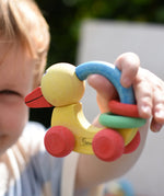Nic organic grip duck wooden push along baby toy in a child's hand.