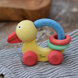 Nic organic grip duck wooden push along baby toy placed on a striped grey cloth.