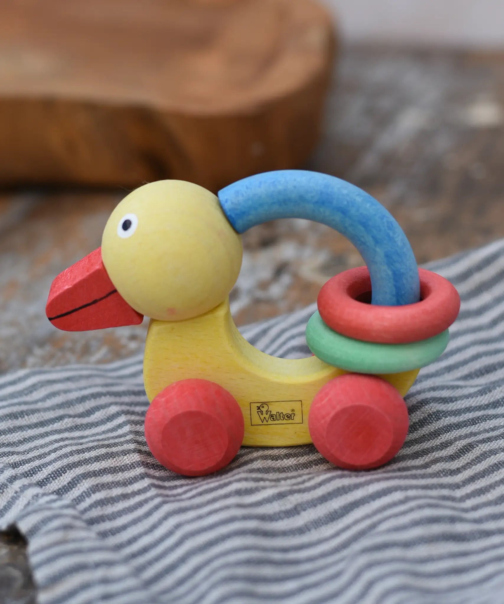 Nic organic grip duck wooden push along baby toy placed on a striped grey cloth.