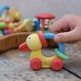 Nic organic grip duck wooden push along baby toy, child pushing the duck along a wooden surface.
