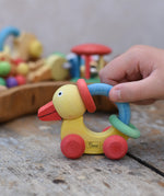 Nic organic grip duck wooden push along baby toy, child pushing the duck along a wooden surface.