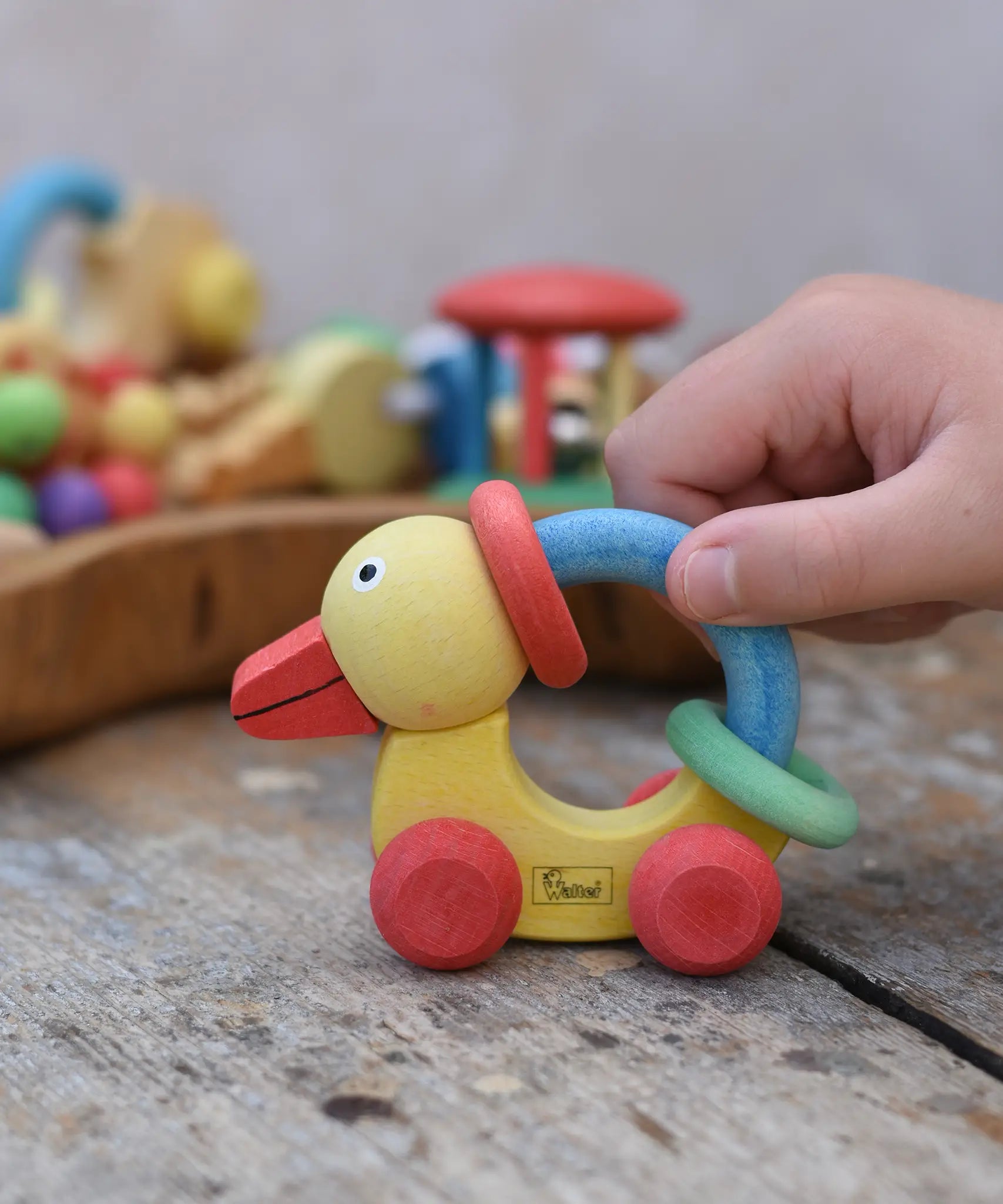 Nic organic grip duck wooden push along baby toy, child pushing the duck along a wooden surface.