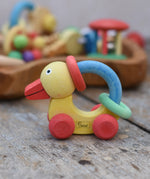 Nic organic grip duck wooden push along baby toy placed on a wooden surface.