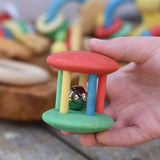 Nic organic jingle bell wooden roller baby toy in a child's hand.