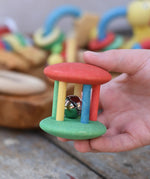 Nic organic jingle bell wooden roller baby toy in a child's hand.