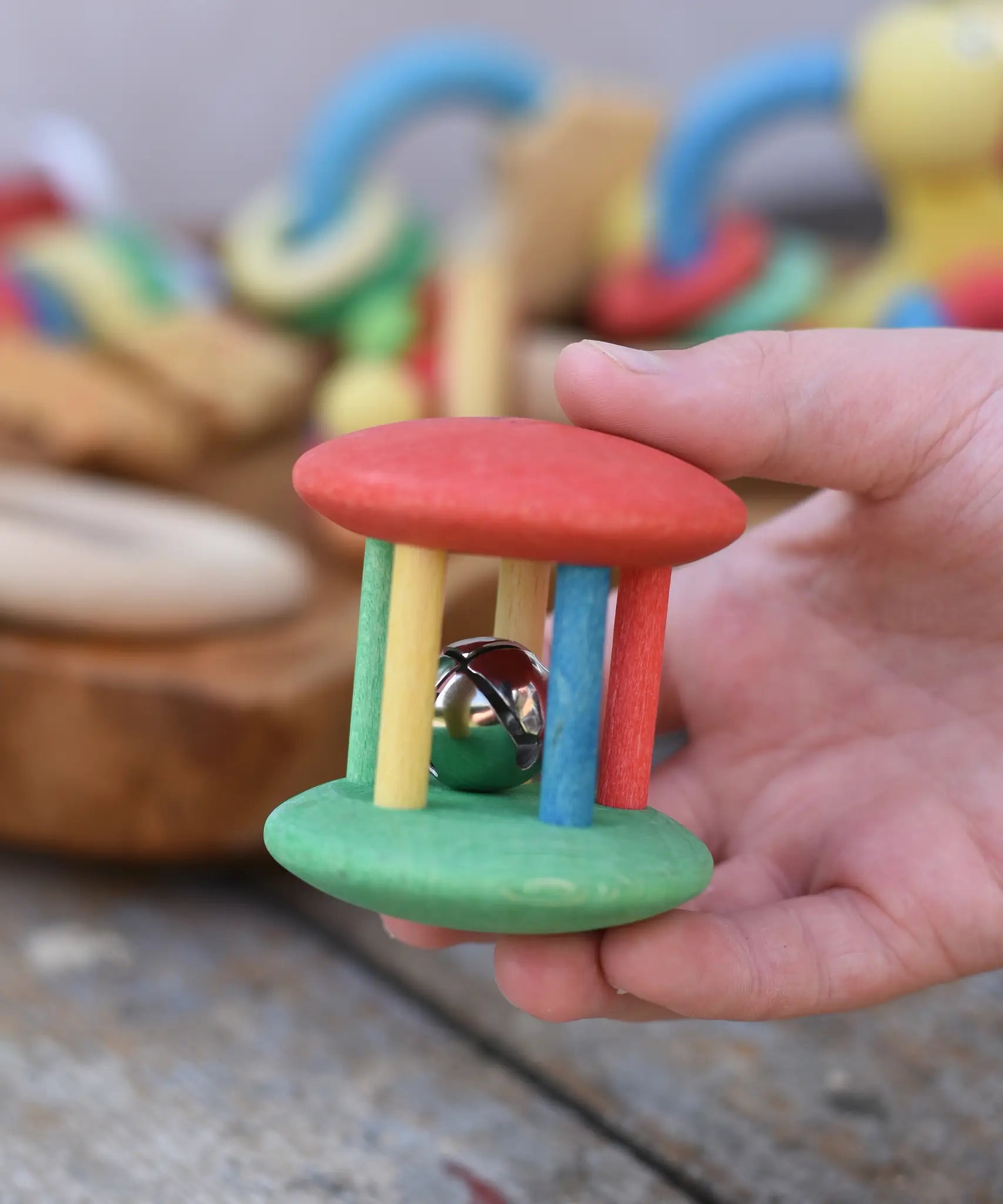 Nic organic jingle bell wooden roller baby toy in a child's hand.