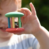 Nic organic jingle bell wooden roller baby toy in a child's hand. 
