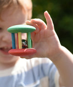 Nic organic jingle bell wooden roller baby toy in a child's hand. 