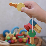 Nic organic wooden grasping keyring set in  a child's hand held up by the yellow key. 
