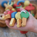 Nic organic wooden grasping keyring set in a child's hand. Four wooden keys on a rope keyring.