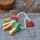 Nic organic wooden grasping keyring set placed on a grey striped cloth. 