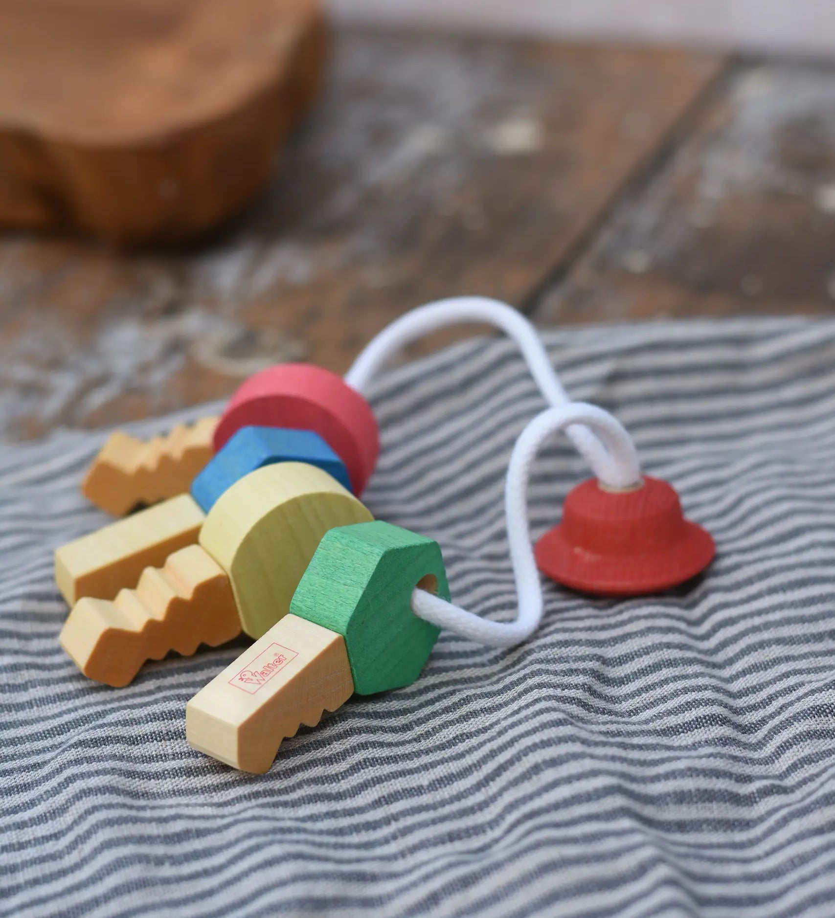 Nic organic wooden grasping keyring set placed on a grey striped cloth. 