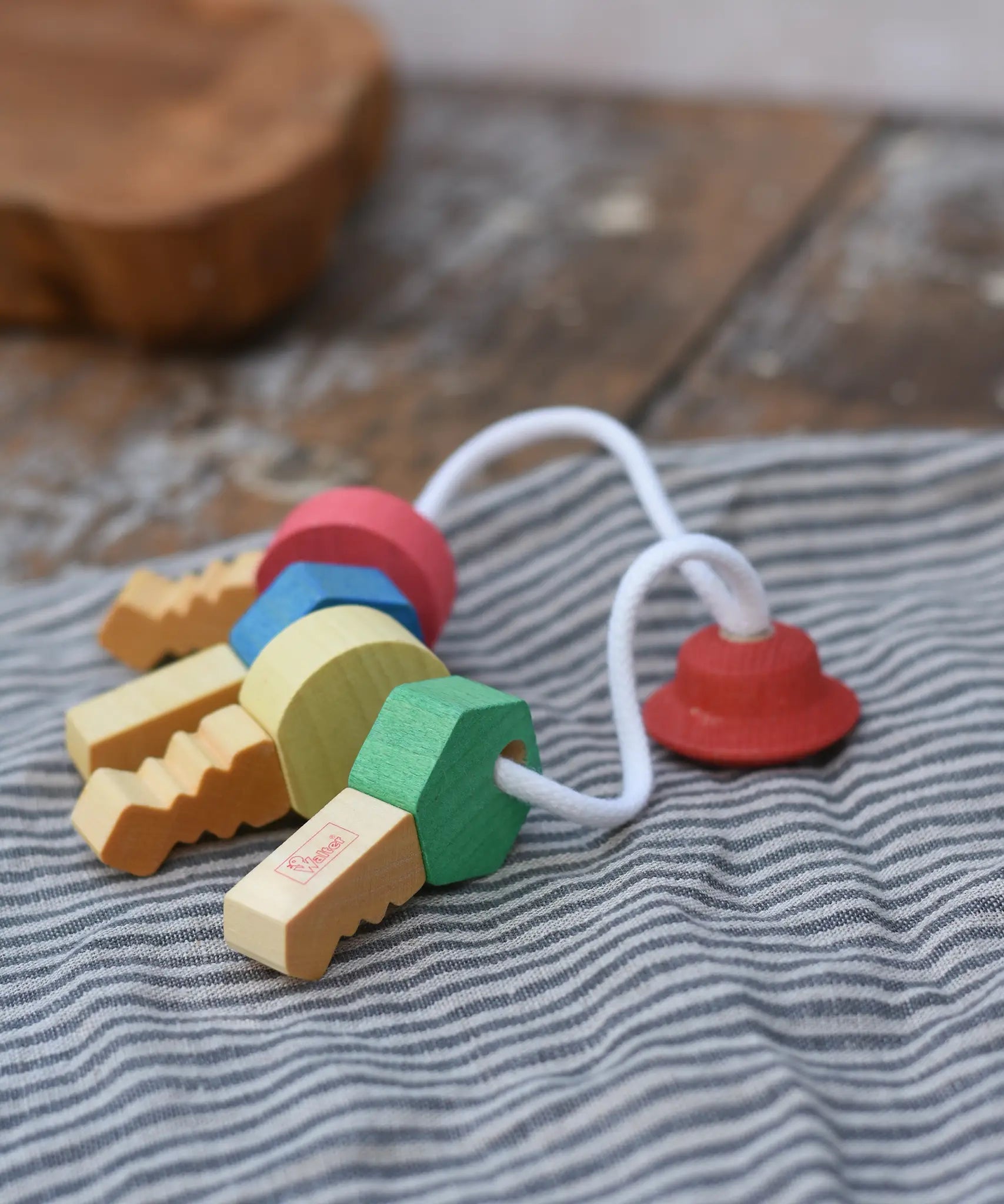 Nic organic wooden grasping keyring set placed on a grey striped cloth. 