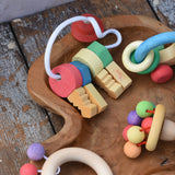 Nic organic wooden grasping keyring set placed in a wooden dish with other wooden toys. 