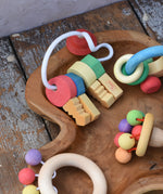 Nic organic wooden grasping keyring set placed in a wooden dish with other wooden toys. 