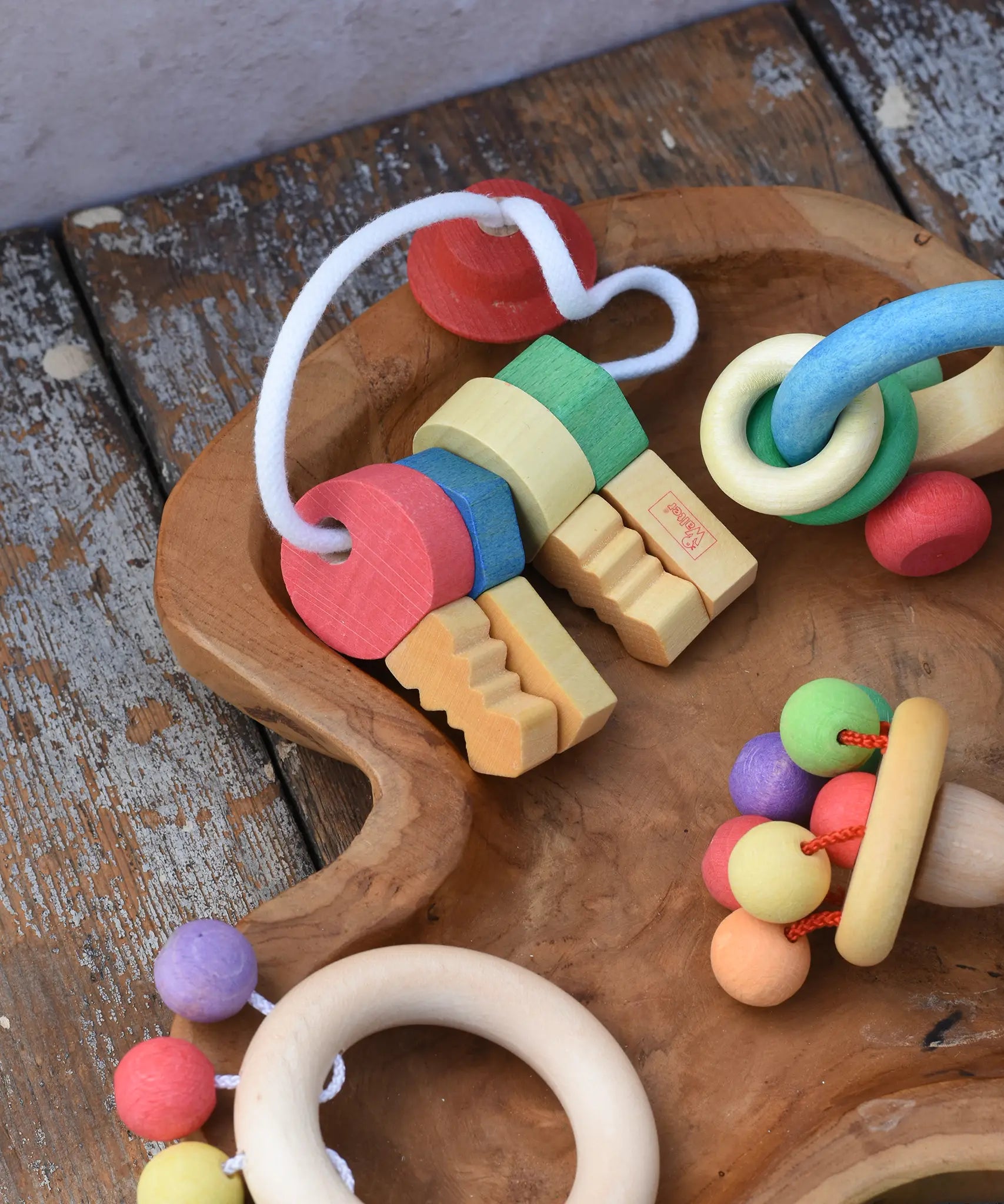 Nic organic wooden grasping keyring set placed in a wooden dish with other wooden toys. 