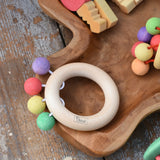 Nic organic teething ring wooden baby toy placed on a wooden dish with other wooden baby toys. 