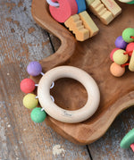 Nic organic teething ring wooden baby toy placed on a wooden dish with other wooden baby toys. 