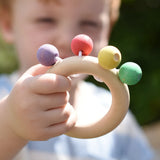 Nic organic teething ring wooden baby toy in a child's hand.