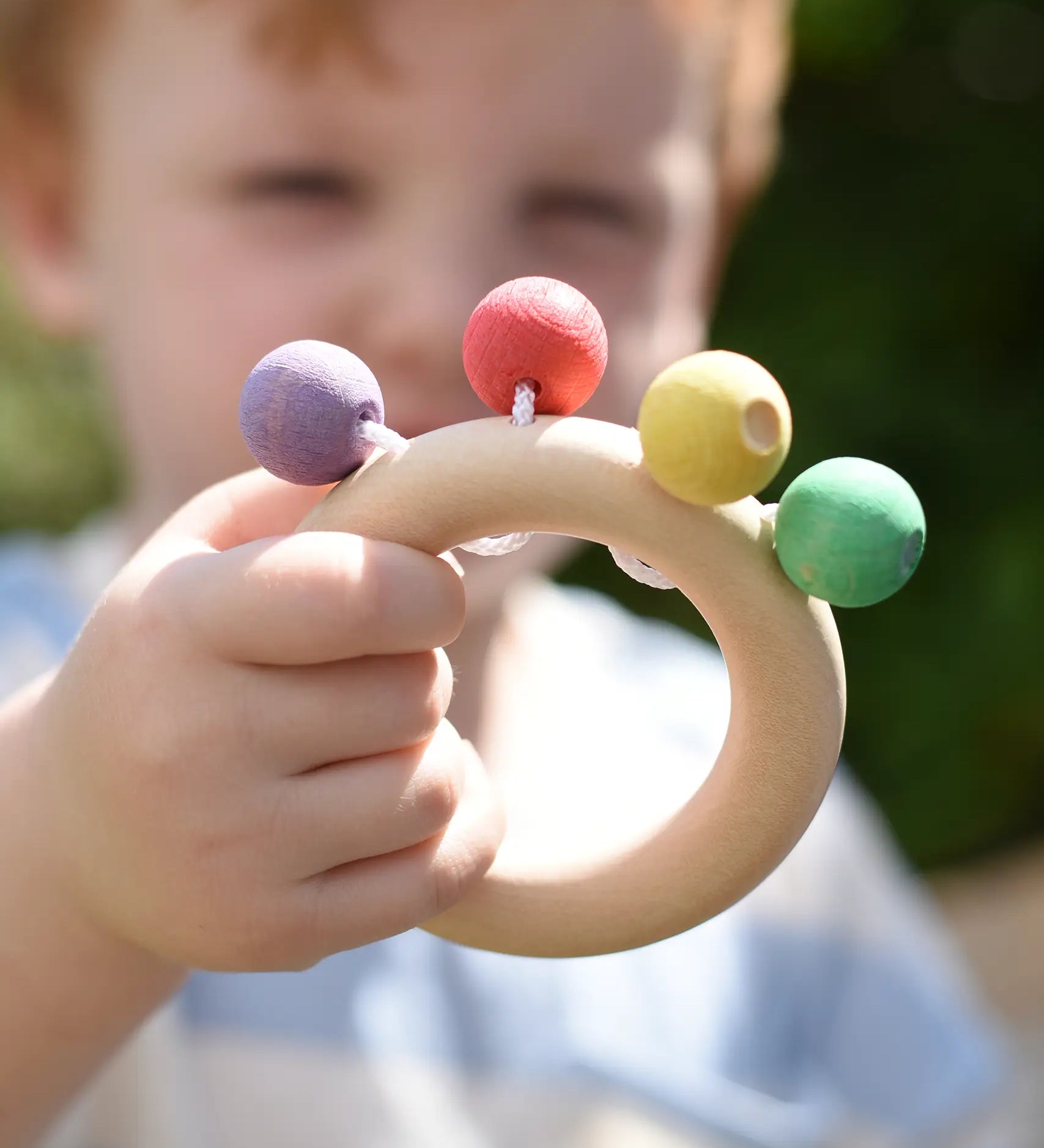 Nic organic teething ring wooden baby toy in a child's hand.