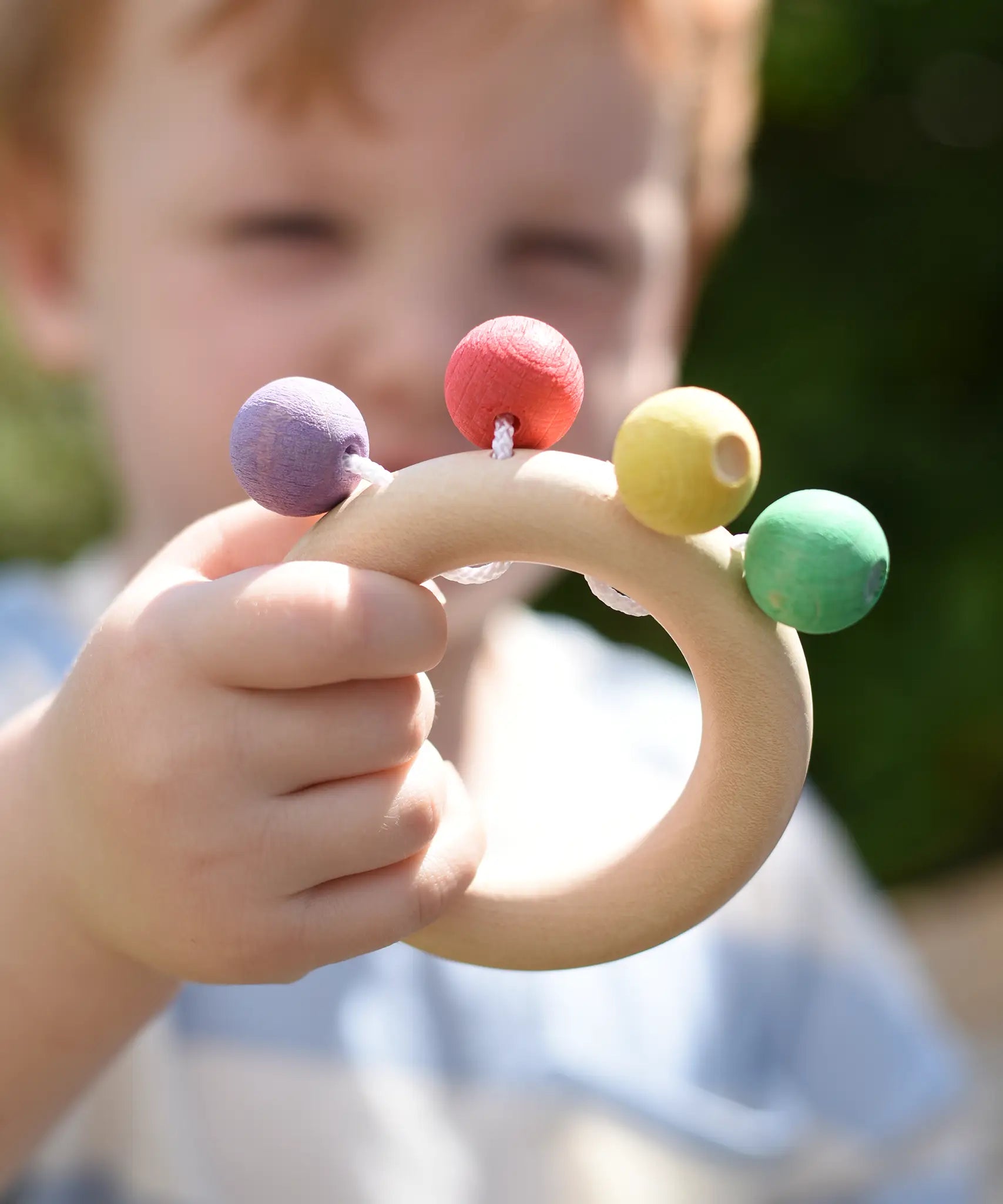 Nic organic teething ring wooden baby toy in a child's hand.