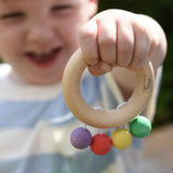 Nic organic teething ring wooden baby toy held by a child with his hand stretched out in front of him.