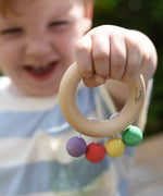 Nic organic teething ring wooden baby toy held by a child with his hand stretched out in front of him.