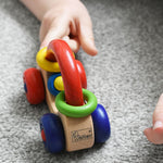 A close up of the Nic First Wooden Car Baby Push-Along Toy being pushed by a child's hand. 