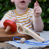 Nic Toys wooden red spinning top with the pieces separated. Features a wooden handle for handling the spinner top with a blue cord for spinning the top. 