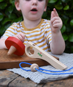 Nic Toys wooden red spinning top with the pieces separated. Features a wooden handle for handling the spinner top with a blue cord for spinning the top. 