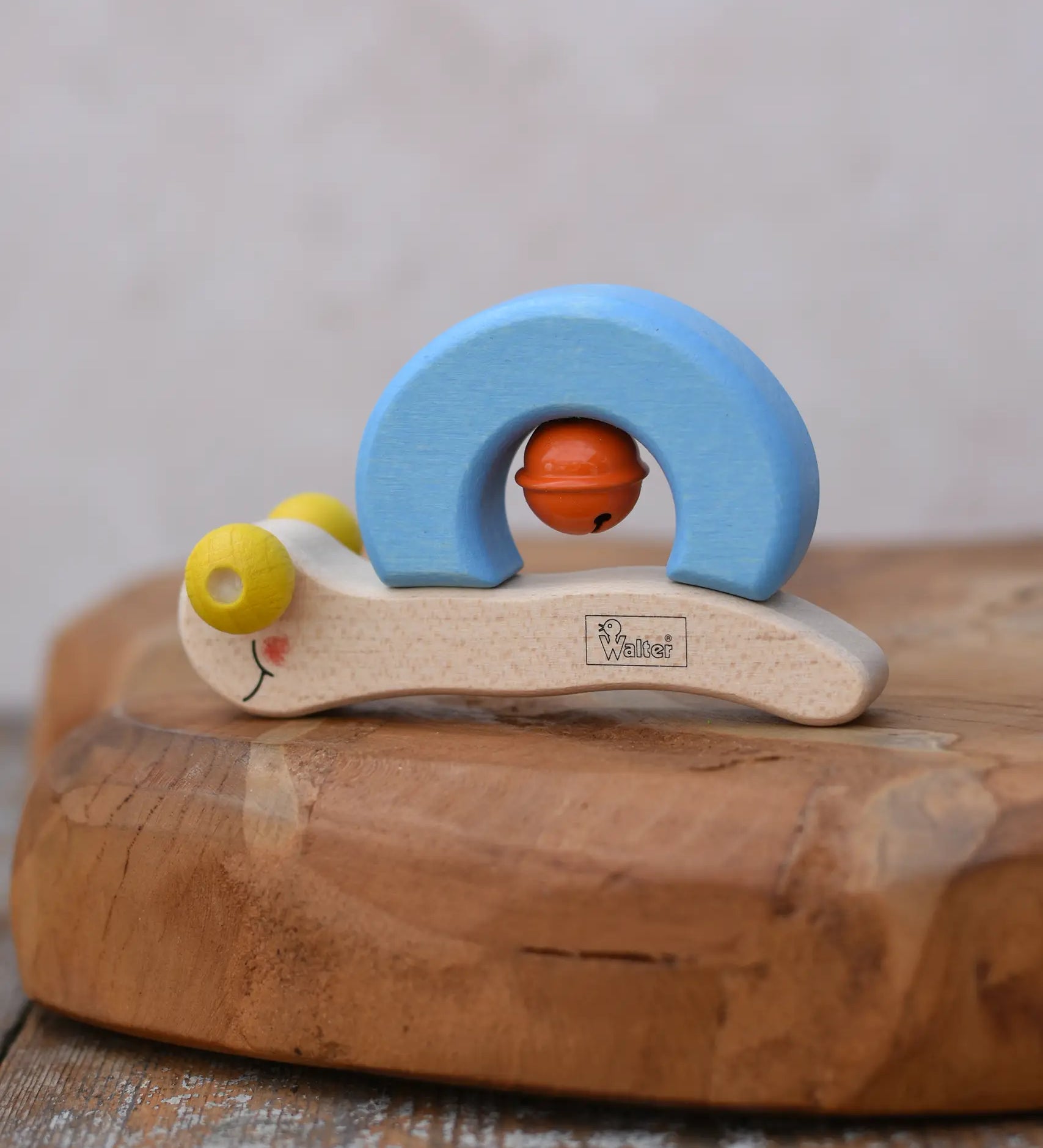 Nic snail baby grasping toy. A light wood and blee wooden toy snail with yellow beads for eyes and an orange bell. 