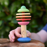 Child holding the Nic Toys bio wooden rattling tree baby toy. Coloured disks for making a noise and a wooden handle for grip.
