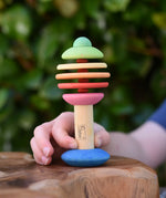 Child holding the Nic Toys bio wooden rattling tree baby toy. Coloured disks for making a noise and a wooden handle for grip.